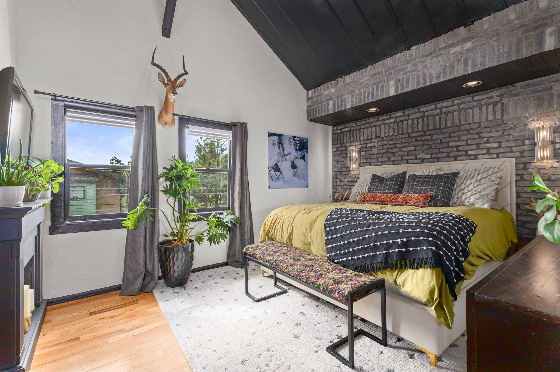Primary bedroom with brick wall and black timber ceiling
